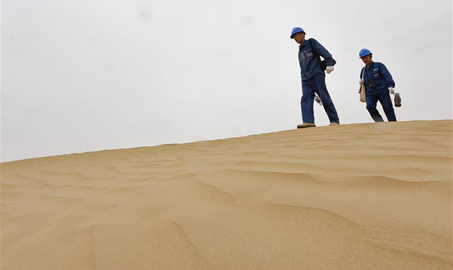 Linemen patrol power line across Taklimakan Desert in China's Xinjiang